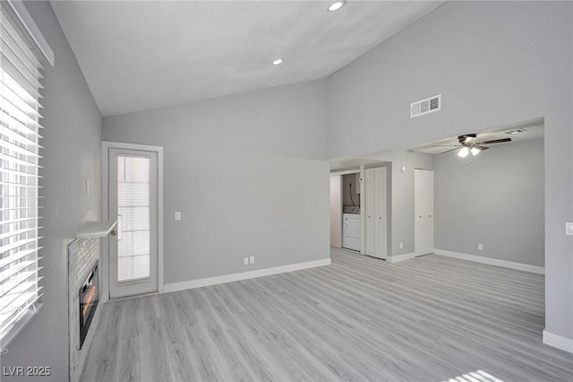 unfurnished living room featuring light wood-type flooring, washing machine and dryer, a healthy amount of sunlight, and ceiling fan