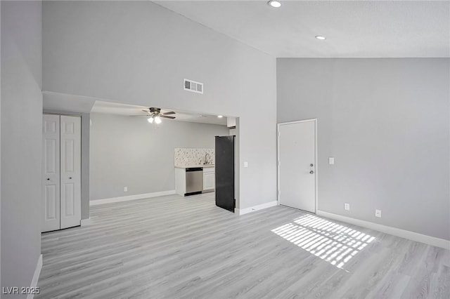 unfurnished living room with ceiling fan, sink, high vaulted ceiling, and light hardwood / wood-style flooring