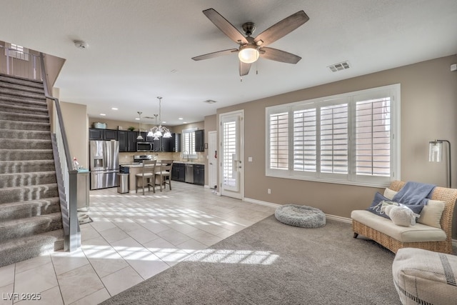 tiled living room with ceiling fan with notable chandelier