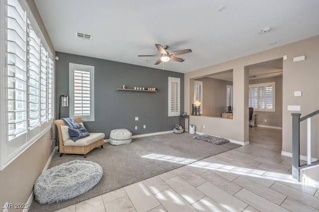 living area featuring ceiling fan, plenty of natural light, and light carpet