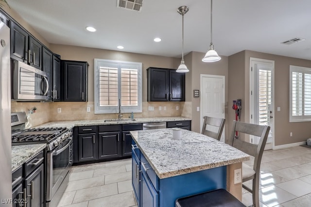 kitchen featuring stainless steel appliances, sink, light tile patterned flooring, blue cabinets, and a center island