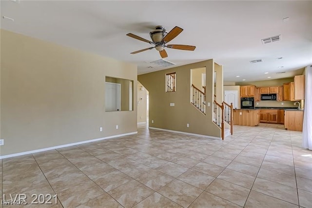 unfurnished living room with ceiling fan, light tile patterned floors, and sink