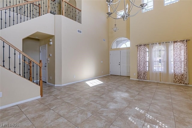 foyer entrance with a towering ceiling, light tile patterned flooring, and an inviting chandelier