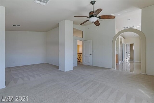 carpeted spare room featuring ceiling fan and a high ceiling