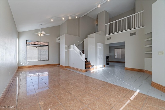 tiled spare room with ceiling fan and a towering ceiling