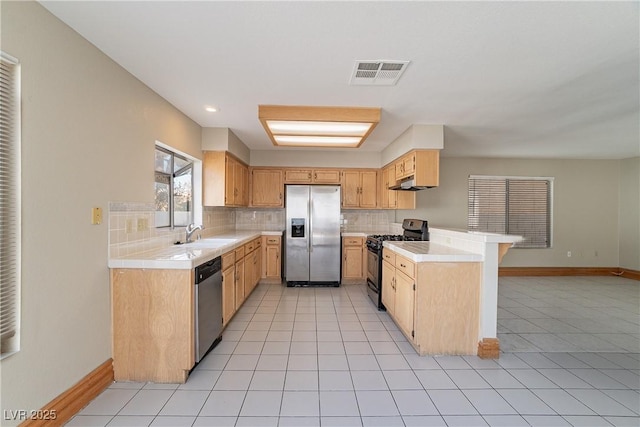 kitchen featuring tasteful backsplash, kitchen peninsula, sink, light tile patterned flooring, and appliances with stainless steel finishes