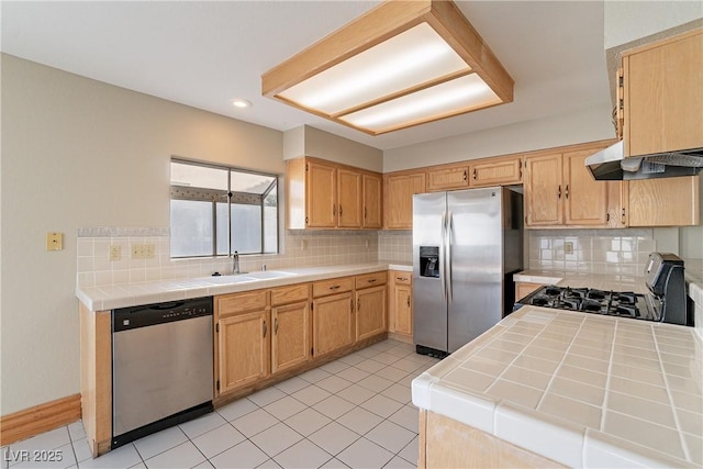 kitchen featuring range hood, appliances with stainless steel finishes, tile countertops, and sink