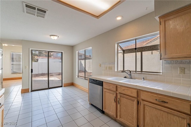 kitchen featuring tile counters, backsplash, light tile patterned flooring, stainless steel dishwasher, and sink