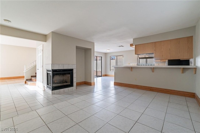 unfurnished living room with light tile patterned flooring and a tiled fireplace