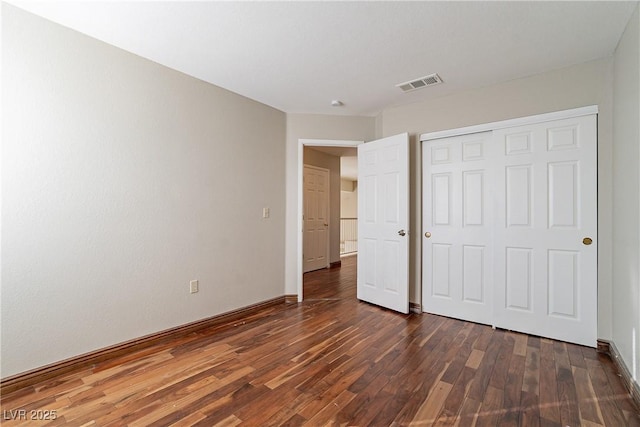 unfurnished bedroom with a closet and dark hardwood / wood-style flooring