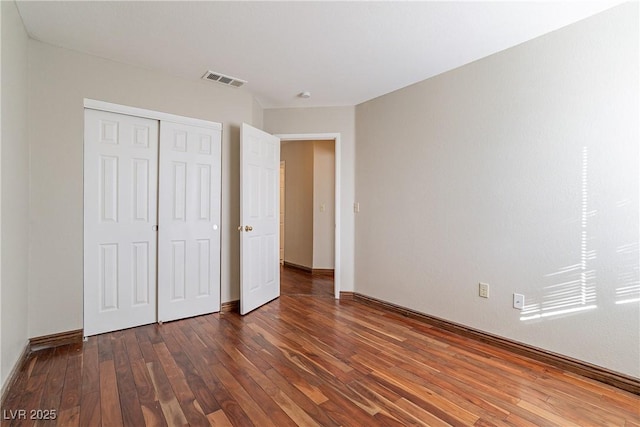 unfurnished bedroom with dark wood-type flooring and a closet