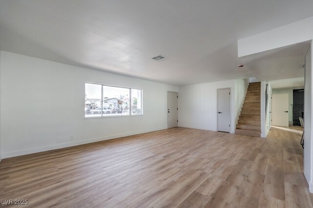 unfurnished room featuring a brick fireplace and light hardwood / wood-style floors