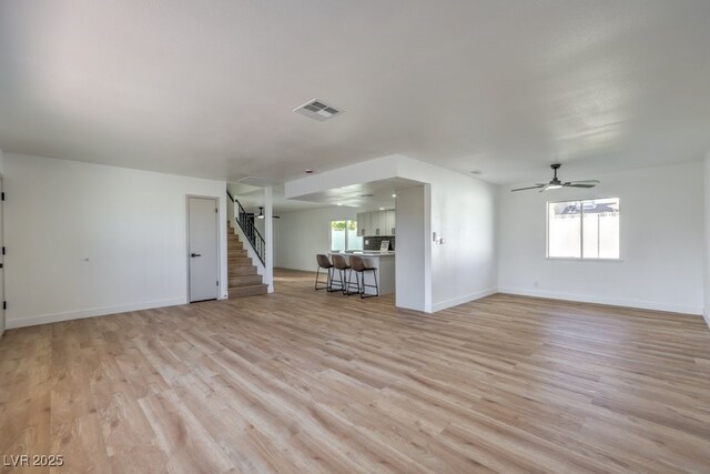 unfurnished living room with ceiling fan, plenty of natural light, and light hardwood / wood-style flooring