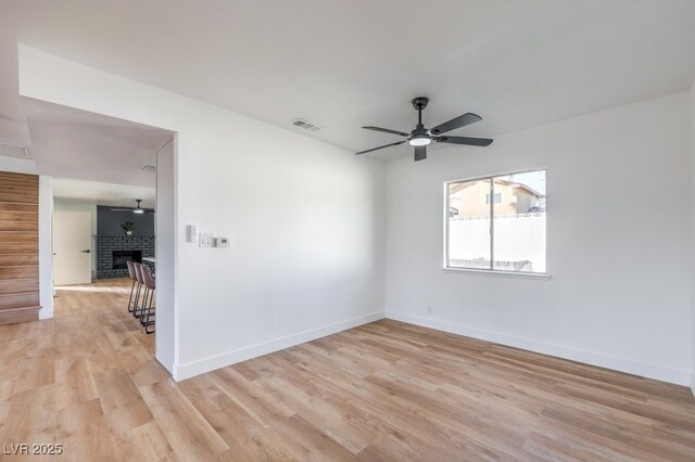 empty room featuring ceiling fan, light hardwood / wood-style flooring, and a fireplace