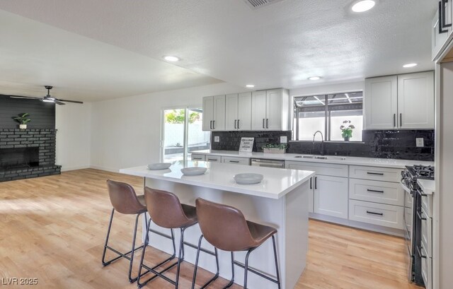 kitchen with white cabinetry, a brick fireplace, appliances with stainless steel finishes, sink, and a center island