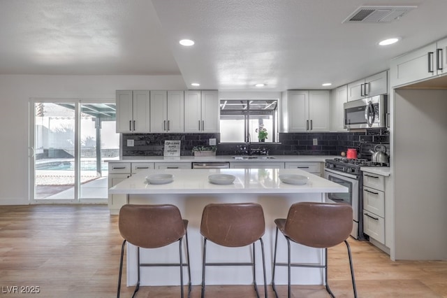 kitchen featuring a wealth of natural light, white cabinets, a center island, stainless steel appliances, and sink