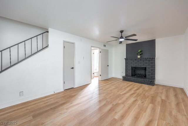 unfurnished living room featuring a brick fireplace, light hardwood / wood-style flooring, and ceiling fan