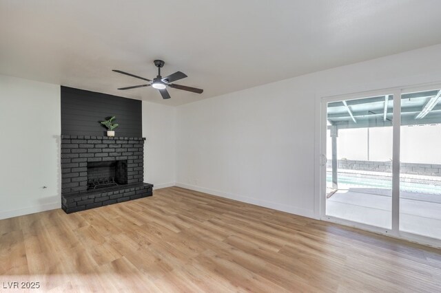 unfurnished living room with light wood-type flooring, a brick fireplace, and ceiling fan