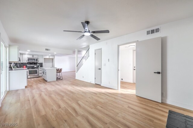 unfurnished living room featuring ceiling fan and light wood-type flooring