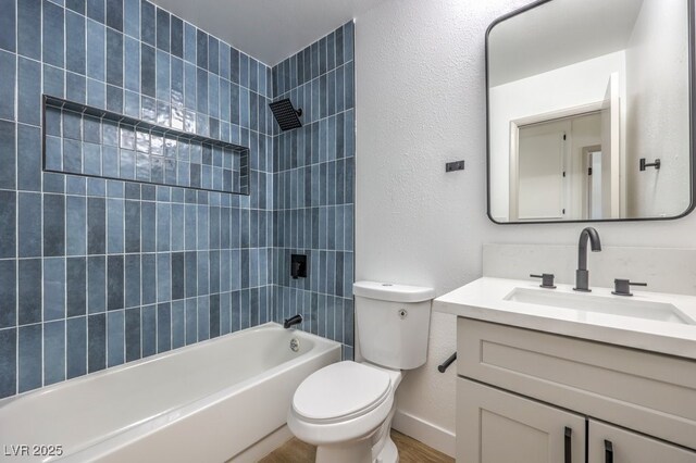 full bathroom featuring toilet, tiled shower / bath, and vanity