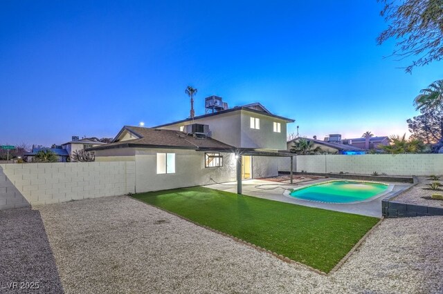 back house at dusk featuring a fenced in pool, cooling unit, a yard, and a patio