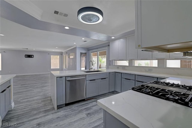 kitchen featuring light stone counters, stainless steel dishwasher, ornamental molding, gray cabinetry, and sink