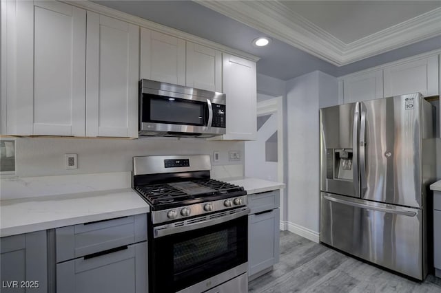 kitchen featuring light wood-type flooring, light stone counters, stainless steel appliances, crown molding, and white cabinets