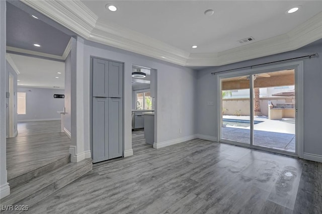 empty room with wood-type flooring, crown molding, and a tray ceiling