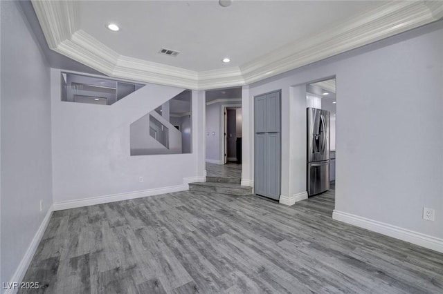 unfurnished room featuring a raised ceiling, wood-type flooring, and ornamental molding