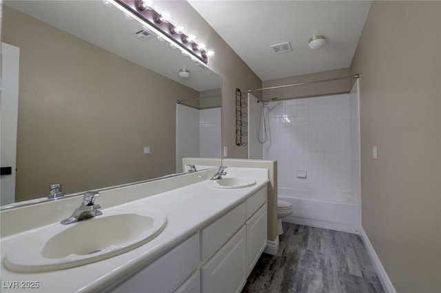 full bathroom with hardwood / wood-style floors, vanity, toilet, and tiled shower / bath