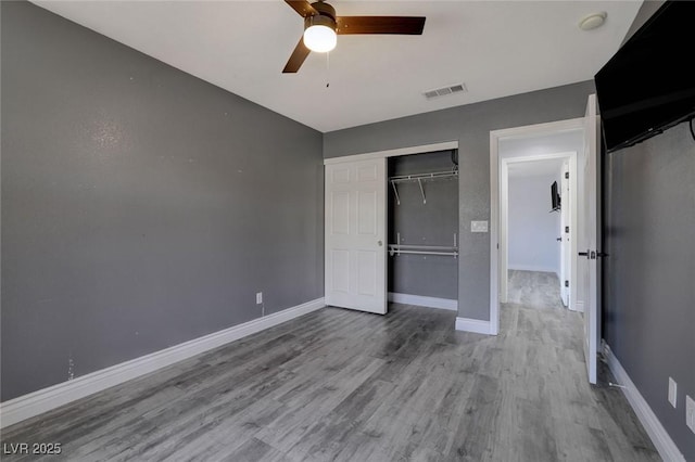 unfurnished bedroom featuring ceiling fan, light hardwood / wood-style floors, and a closet