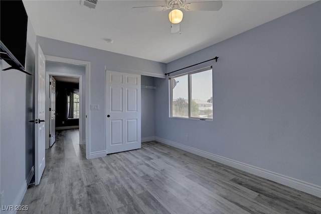 unfurnished bedroom featuring ceiling fan, a closet, and light wood-type flooring