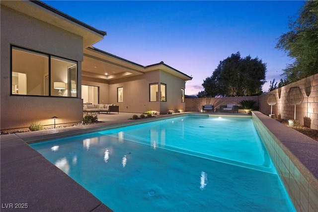 pool at dusk with an outdoor hangout area