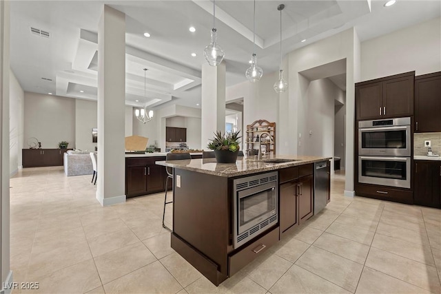 kitchen with a kitchen island with sink, appliances with stainless steel finishes, sink, and dark brown cabinets