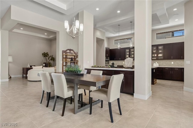 tiled dining space featuring a high ceiling, a raised ceiling, and a notable chandelier