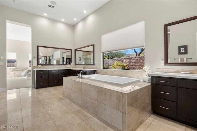 bathroom with tiled bath, tile patterned floors, and vanity