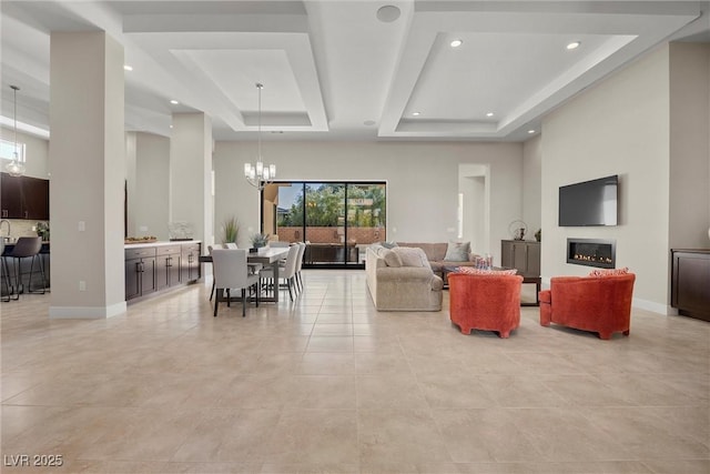 tiled living room featuring a high ceiling, a raised ceiling, and a notable chandelier