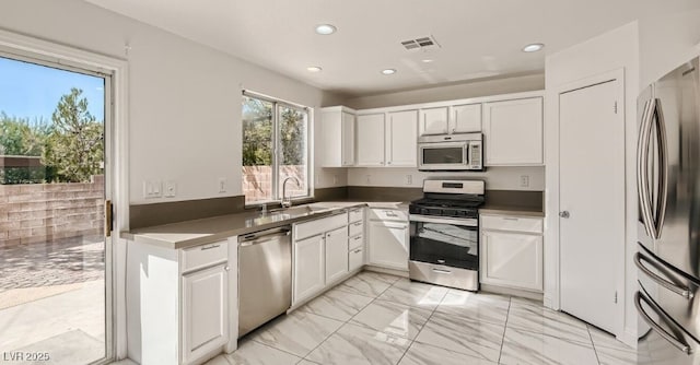 kitchen with stainless steel appliances, white cabinetry, and sink