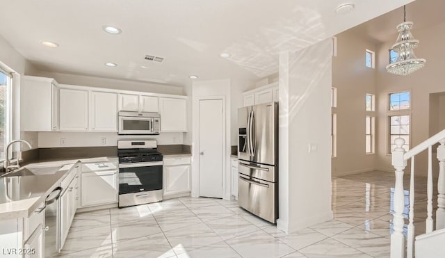 kitchen with white cabinets, appliances with stainless steel finishes, hanging light fixtures, and sink