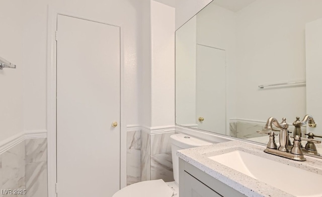 bathroom with vanity, toilet, and tile walls