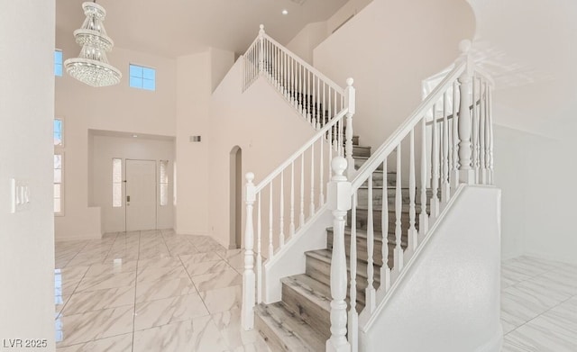 stairs featuring plenty of natural light, a towering ceiling, and a chandelier