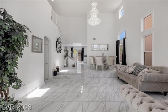 living room featuring a high ceiling, a notable chandelier, and a healthy amount of sunlight