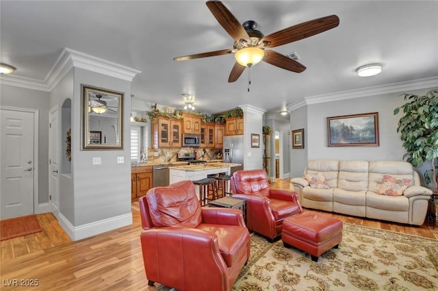 living room with ceiling fan, ornamental molding, and light hardwood / wood-style flooring