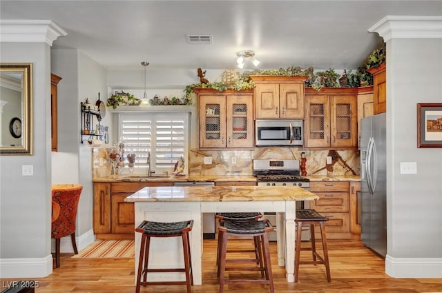 kitchen with a kitchen bar, sink, a center island, appliances with stainless steel finishes, and backsplash