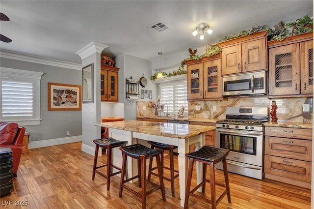 kitchen featuring decorative backsplash, appliances with stainless steel finishes, and light hardwood / wood-style flooring