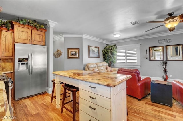 kitchen with a kitchen island, appliances with stainless steel finishes, a breakfast bar area, crown molding, and light hardwood / wood-style flooring