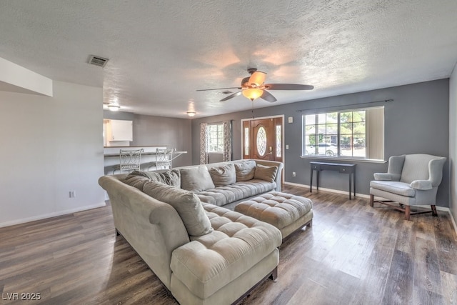 living room with dark hardwood / wood-style floors, ceiling fan, and a textured ceiling