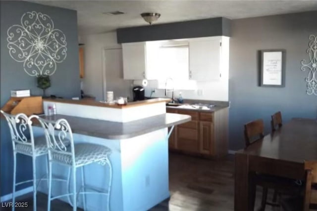 kitchen with hardwood / wood-style floors, a kitchen island, kitchen peninsula, and sink