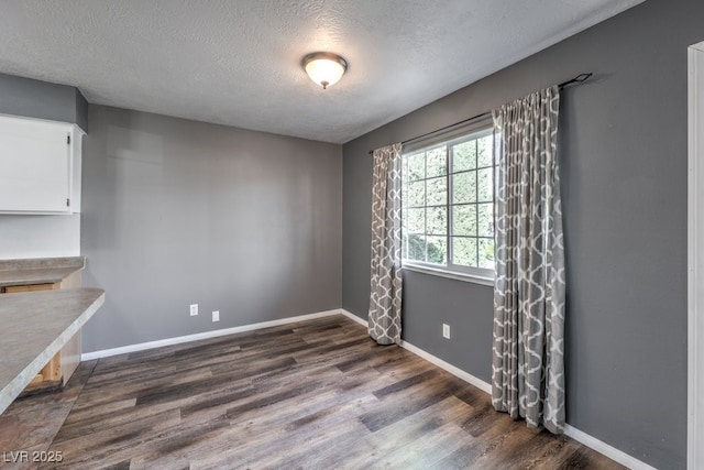 unfurnished room with dark wood-type flooring and a textured ceiling