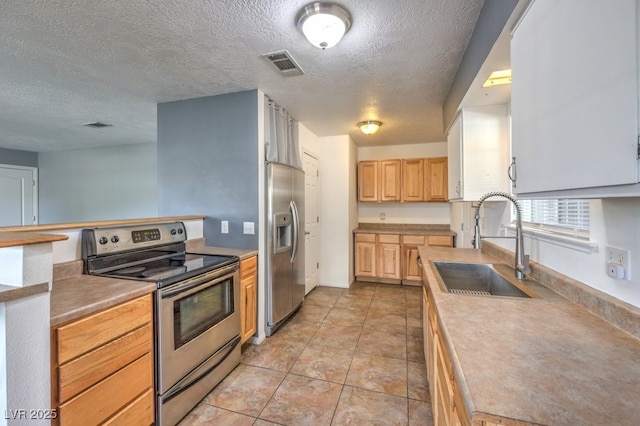 kitchen featuring sink, light brown cabinets, a textured ceiling, light tile patterned flooring, and appliances with stainless steel finishes